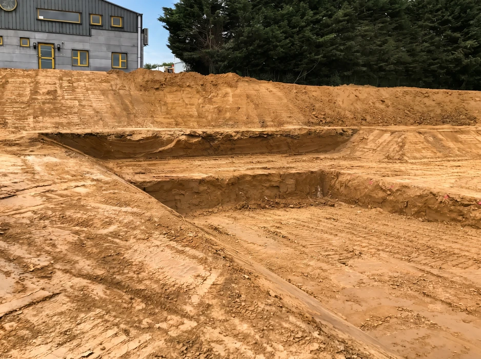 Chantier de terrassement en plein air, excavation profonde en paliers successifs dans un sol sableux ocre