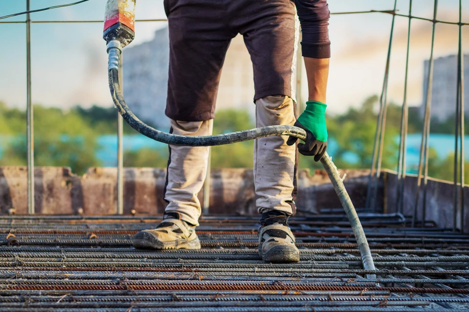 Chantier de construction extérieur avec ouvrier coulant du béton sur ferraillage à l'aide d'une pompe à béton