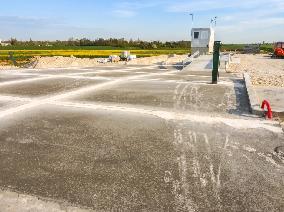 Chantier extérieur en phase de finition, dalle béton fraîchement coulée avec joints de dilatation visibles
