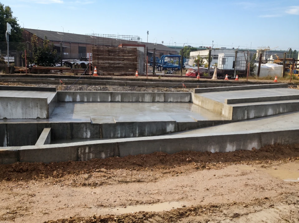 Chantier de construction ext&eacute;rieur avec fondations en b&eacute;ton arm&eacute; fra&icirc;chement coul&eacute;es