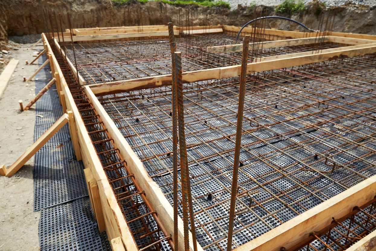 Chantier de construction urbain en extérieur avec ouvriers équipés de casques de sécurité travaillant sur une structure en béton armé